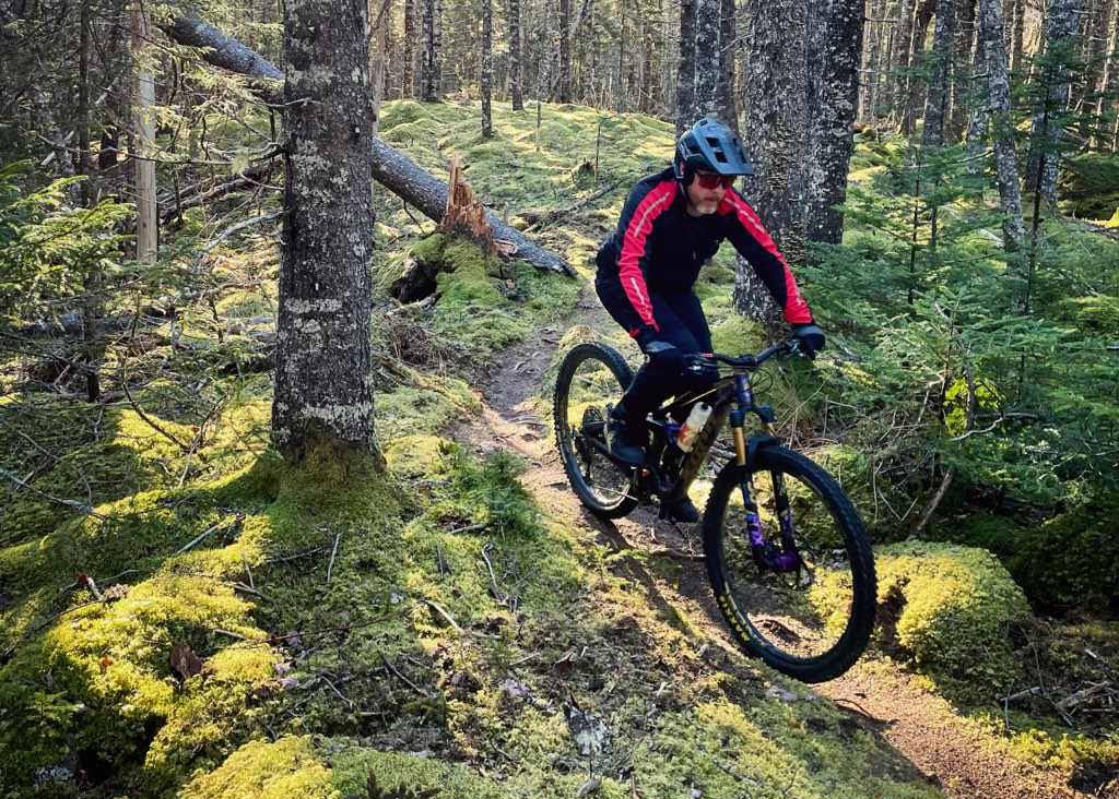 Craig Ross rides his mountain bike through the forest. | Craig Ross fait du vélo tout terrain dans la forêt.